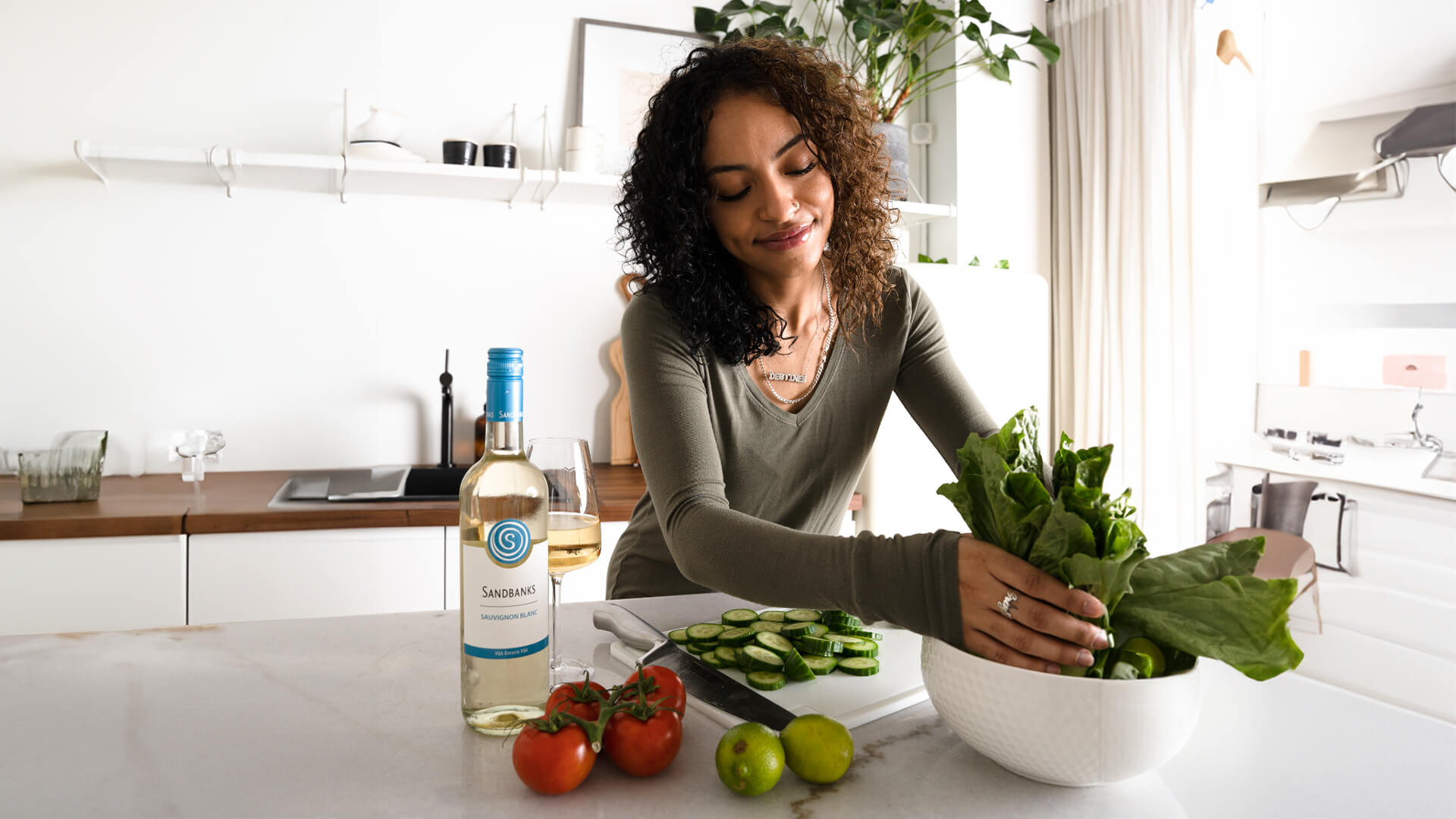 Salad being prepared with a bottle of Sandbanks sauvignon blanc.