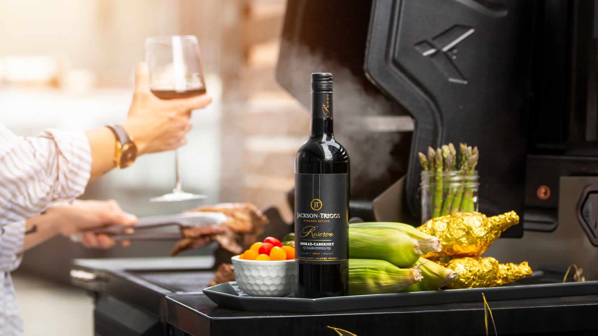 A bottle of Jackson-Triggs Reserve Merlot at a BBQ.