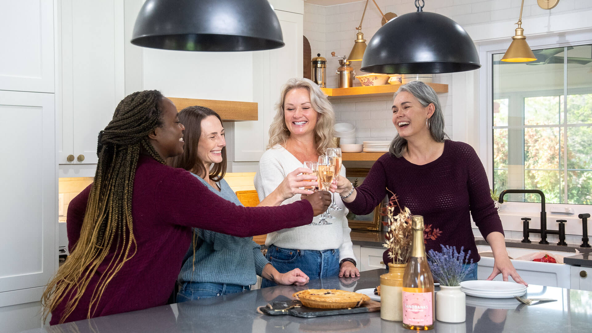 Friends gathered in kitchen enjoying Sandbanks Sparkling Rose.